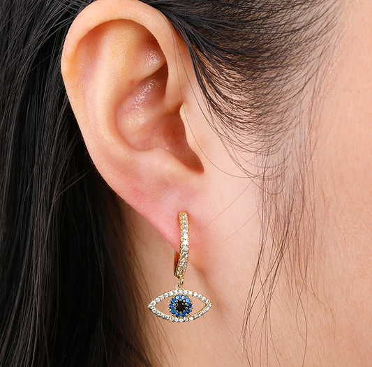 CJ gold-tone hoop earring with pavé crystals and eye-shaped pendant featuring a blue center stone.