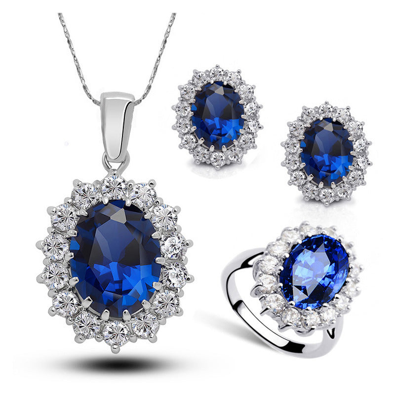 4-piece crystal jewelry set: necklace, earrings, ring with blue oval centerpiece and diamond halo in silver-tone metal