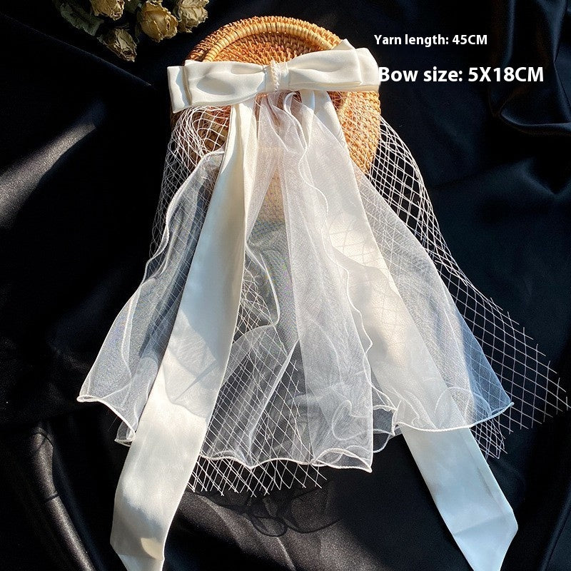 Bow Veil by CJ: white satin bow with tulle veil on a wicker basket