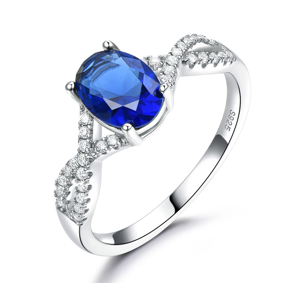 Sterling silver ladies ring with deep blue oval gemstone and pavé diamond accents on split shank