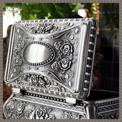 Vintage jewelry box with ornate embossed silver finish, floral relief and beaded border, open lid.