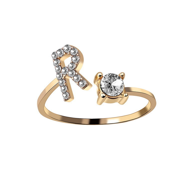 Gold-tone adjustable initial-letter ring with a diamond-studded accent and a solitaire diamond setting