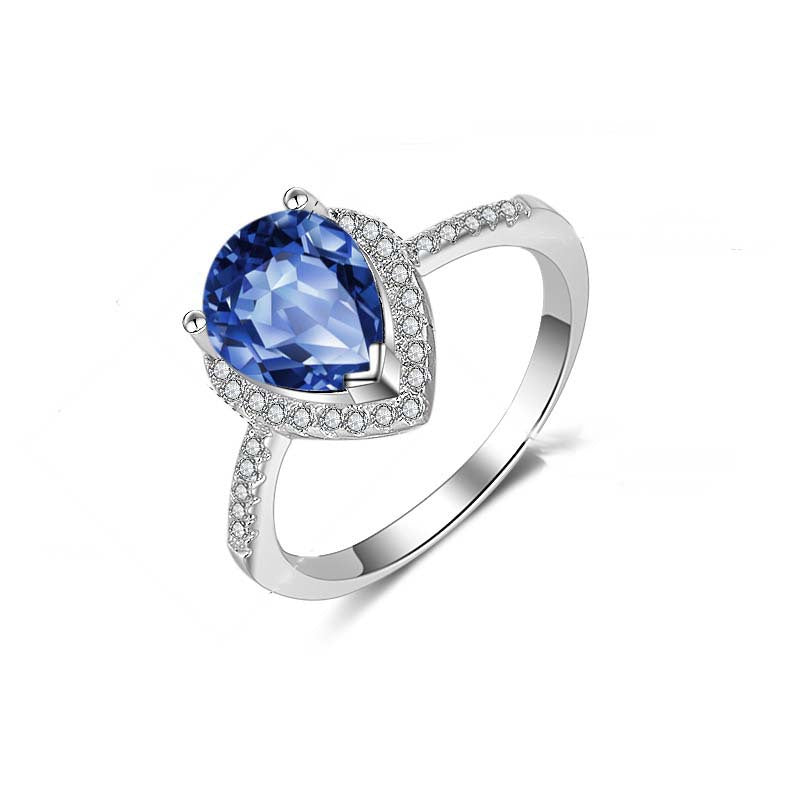 Diamond ring with blue gemstone centerpiece and pave diamonds on a silver band, CJ brand.