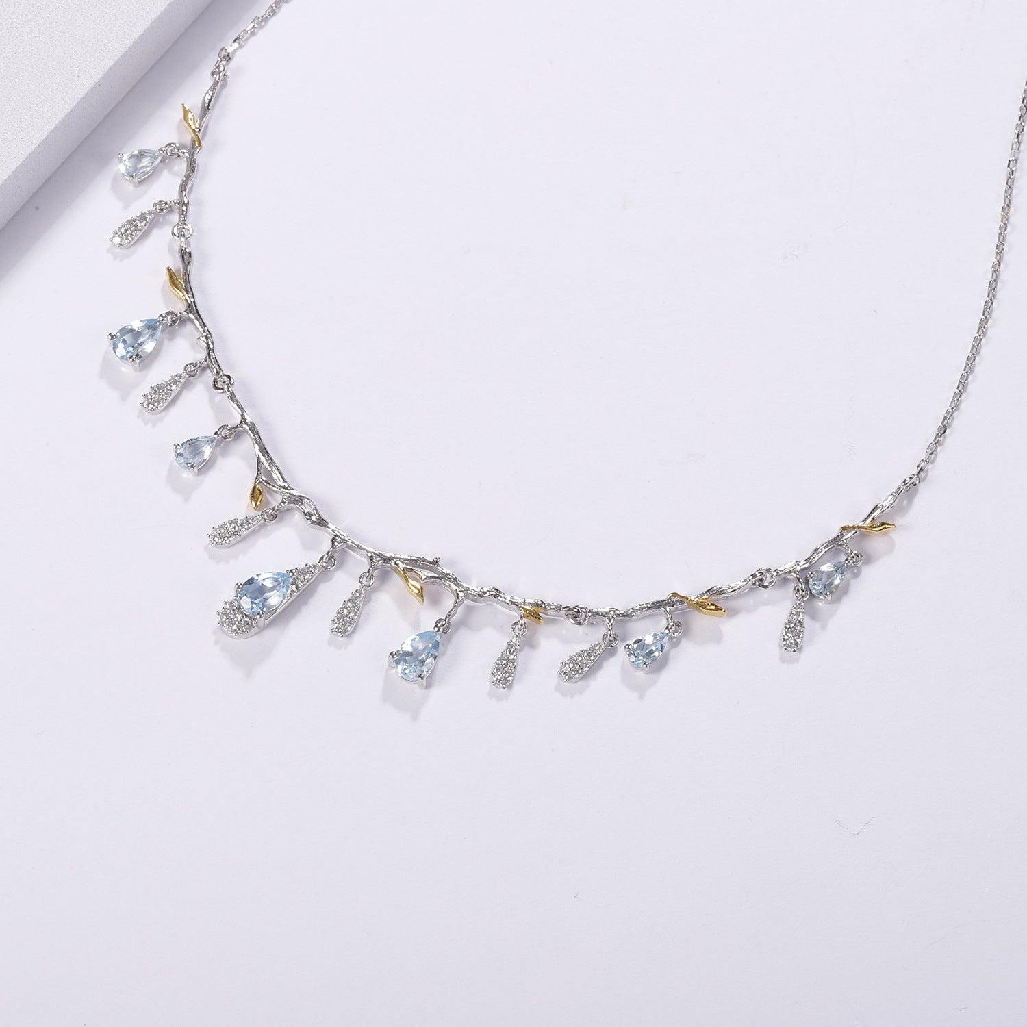 S925 silver natural topaz necklace with blue teardrop gems, crystal charms, and gold-tone leaf accents on a branch chain