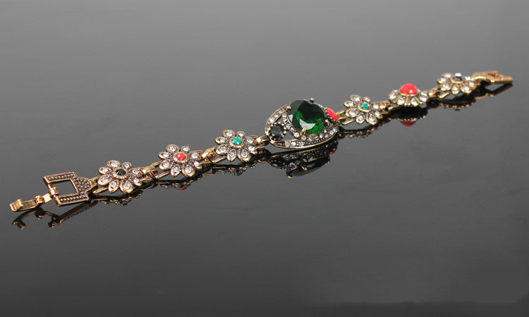 Vintage ethnic style bracelet in rose-gold tone with crystal floral links and a green centerpiece.