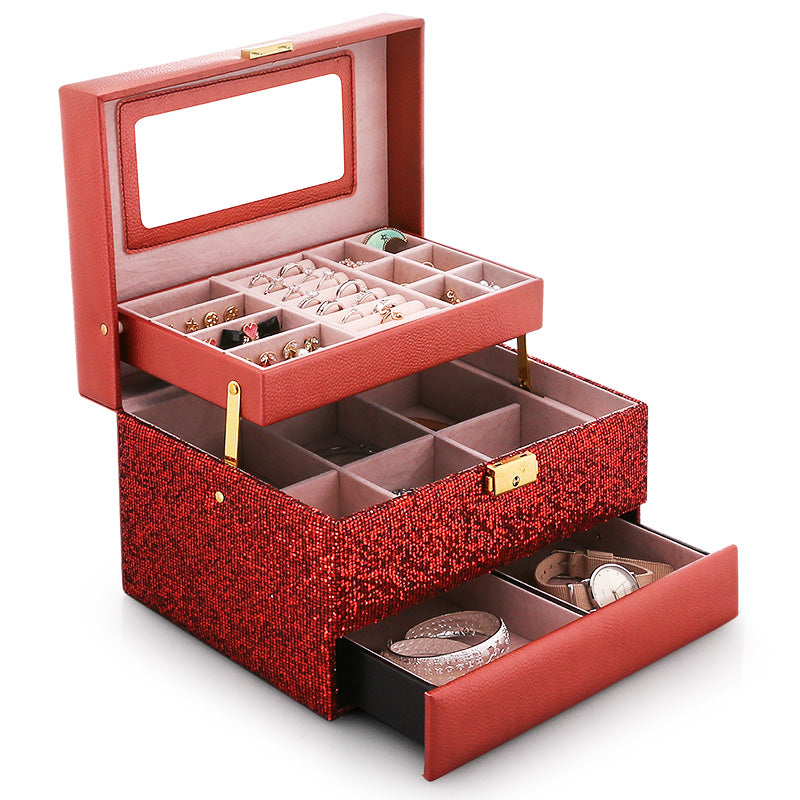 Organizing jewelry storage box with red glitter exterior and pink interior, dual-tier tray holding rings and a watch