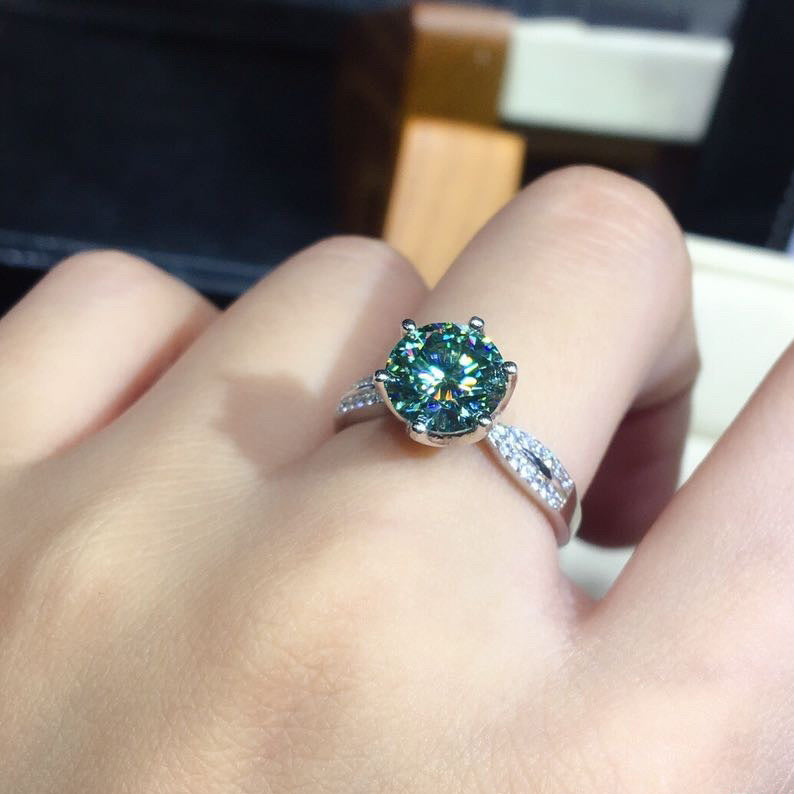 Adjustable sterling silver ring with blue-green moissanite center stone and pave band