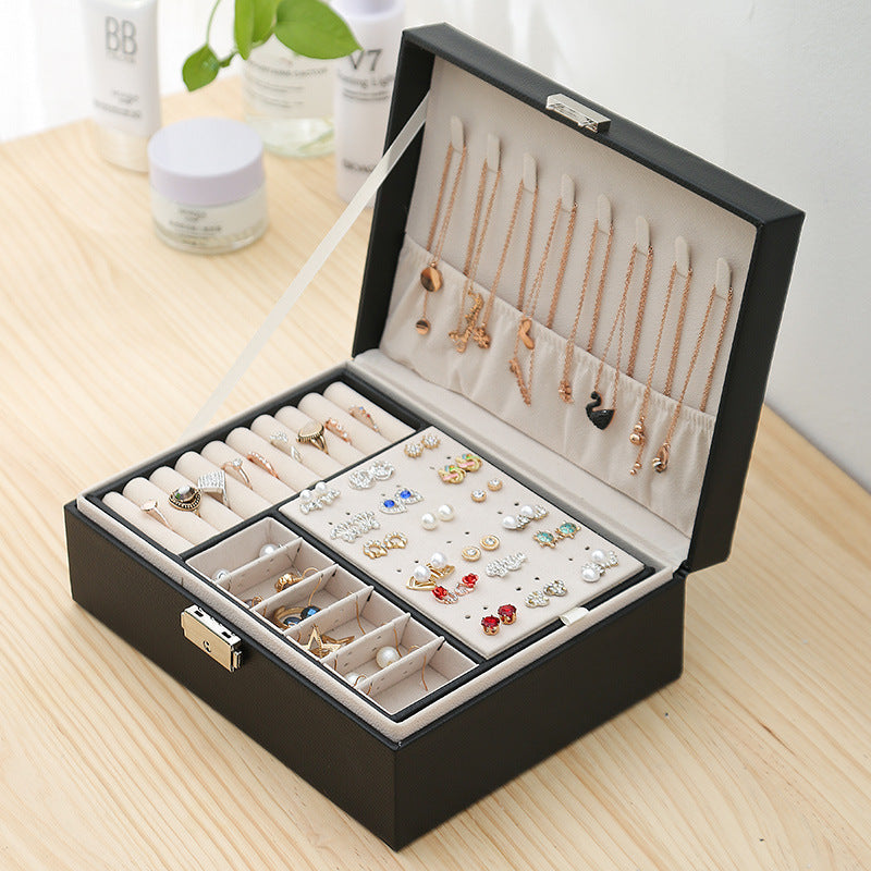 Double-layer black leather jewelry storage box with beige interior and ring, earring, necklace compartments.