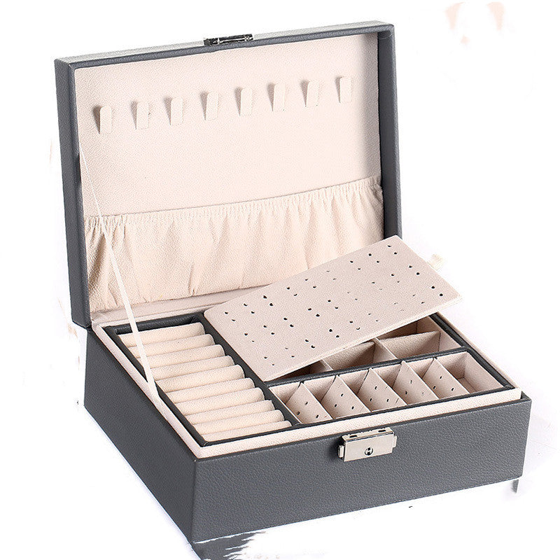 Double-layer leather jewelry storage box in dark gray with beige interior; ring cushions and divided compartments.