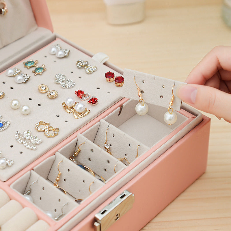 Double-layer leather jewelry storage box by Edenista in pink, with multiple compartments holding many earrings.