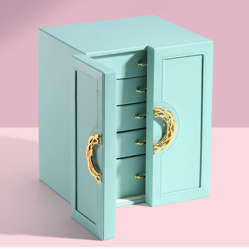 Leather jewelry box in turquoise with gold-tone hardware; dual doors open to reveal four drawers.