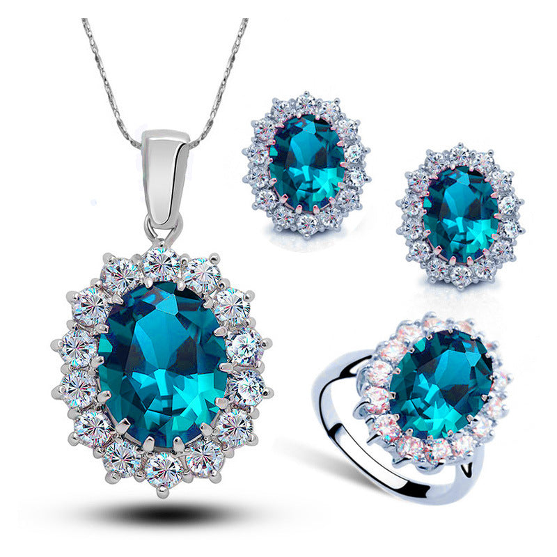 Bridal 4-piece crystal jewelry set: necklace, earrings, and ring with blue oval centers and a halo of clear crystals.
