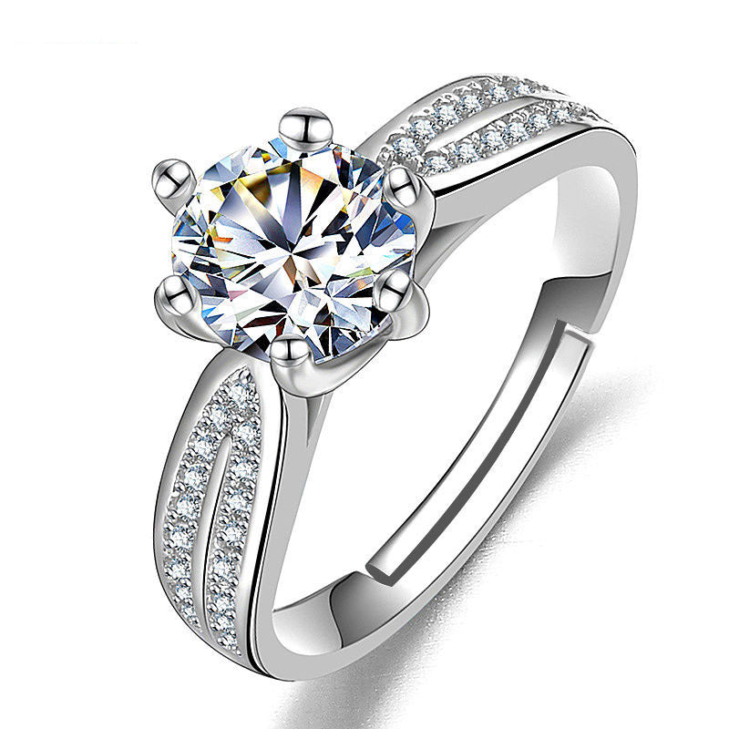 Women's ring with a large round moissanite centerpiece and pavé-set shoulders on a silver band