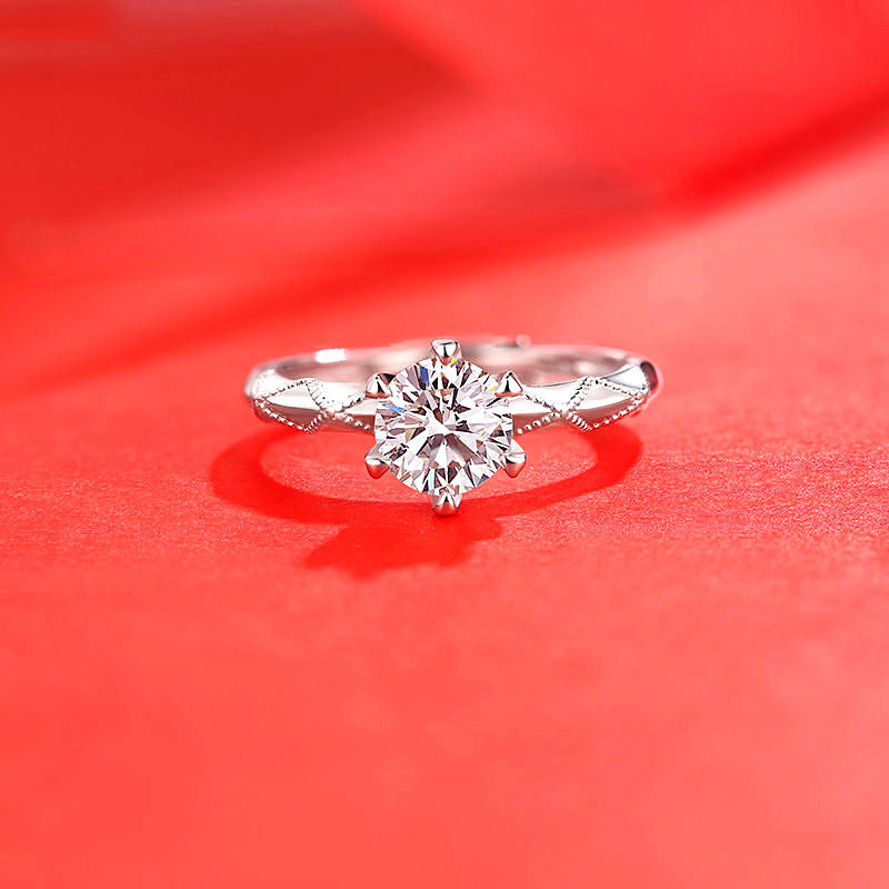 Ring with round imitation moissan diamond in a six-prong setting on a silver band with decorative accents