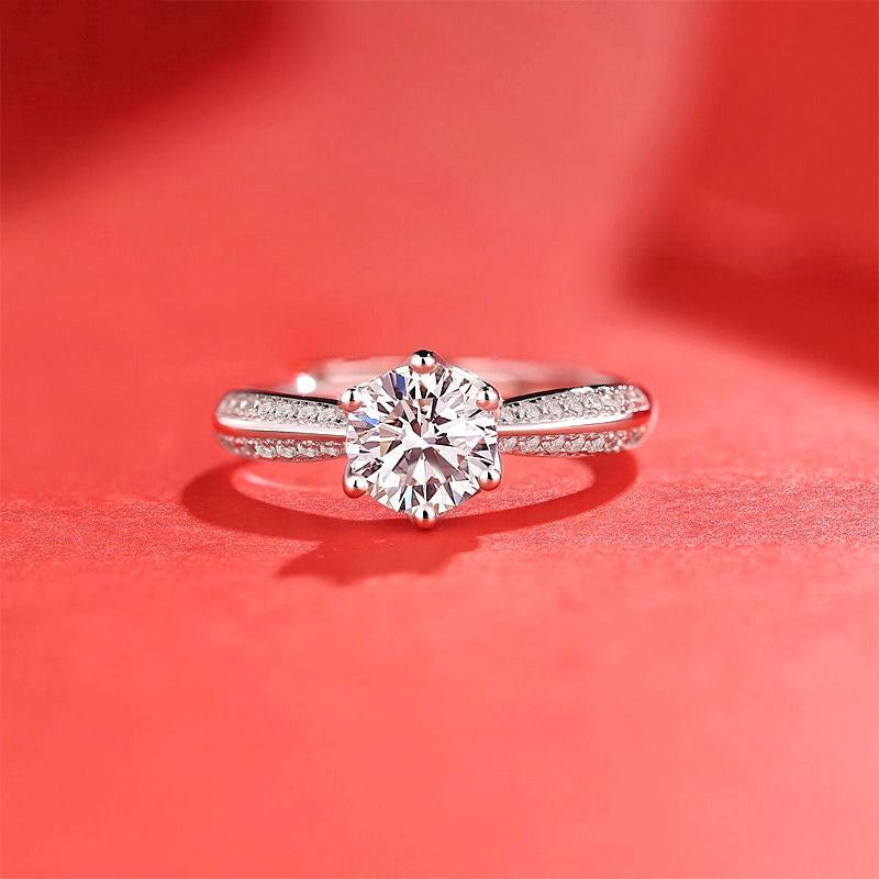 Women's moissanite ring with a round center stone and pavé-set silver band