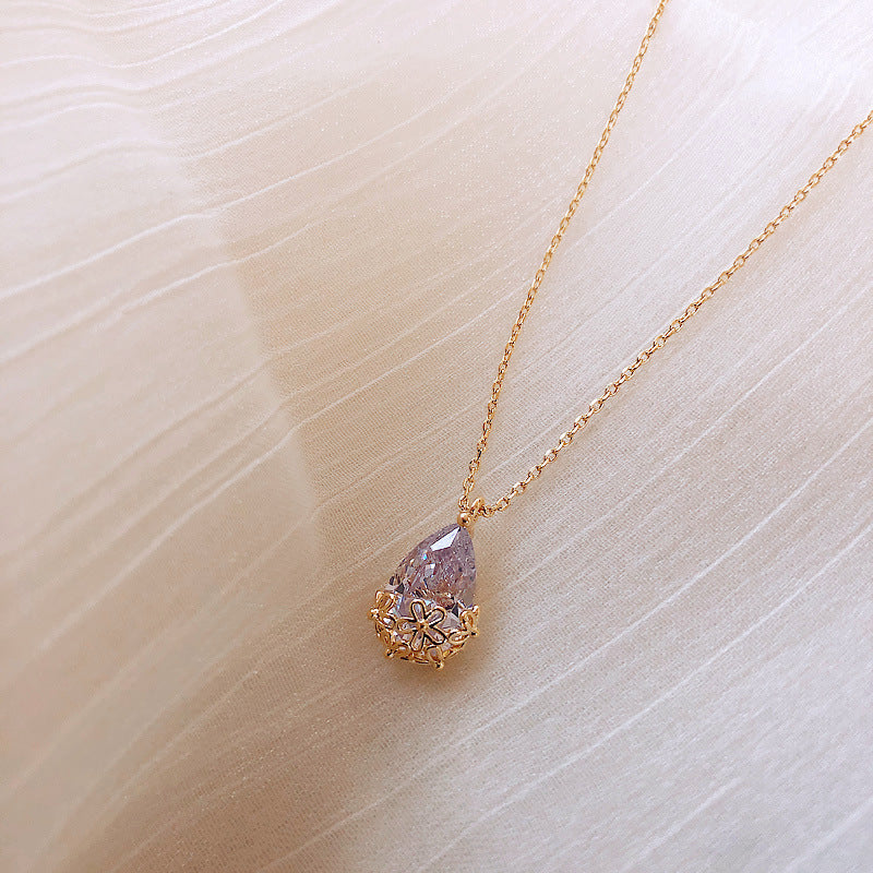 Gold-tone water-drop pendant necklace with lavender crystal and floral bezel on delicate chain