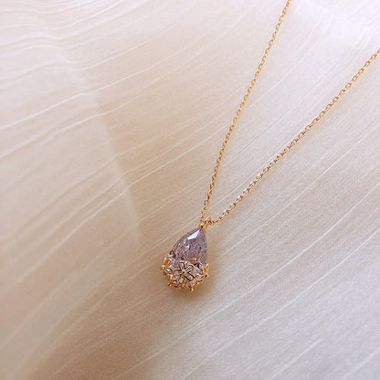Gold-tone water-drop pendant necklace with lavender crystal and floral bezel on delicate chain