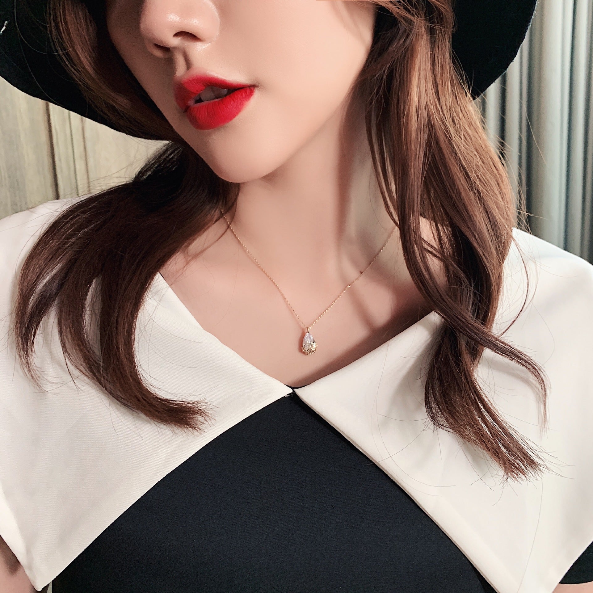 Crystal water-drop pendant necklace on a delicate gold-tone chain, adjustable length.
