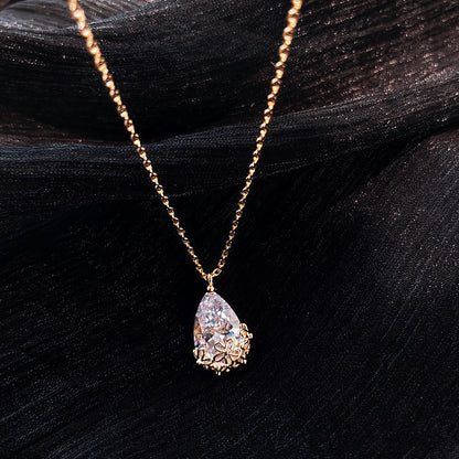 Crystal water drop pendant necklace in gold-tone with floral-lined setting on adjustable chain.