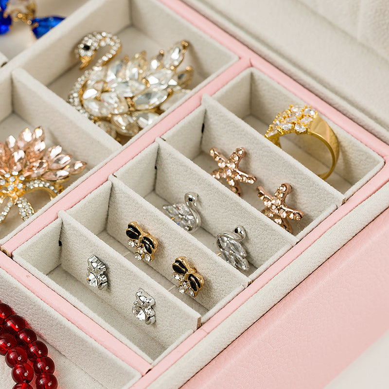 Jewelry box by edenista in pink with beige divided compartments and assorted jewelry.