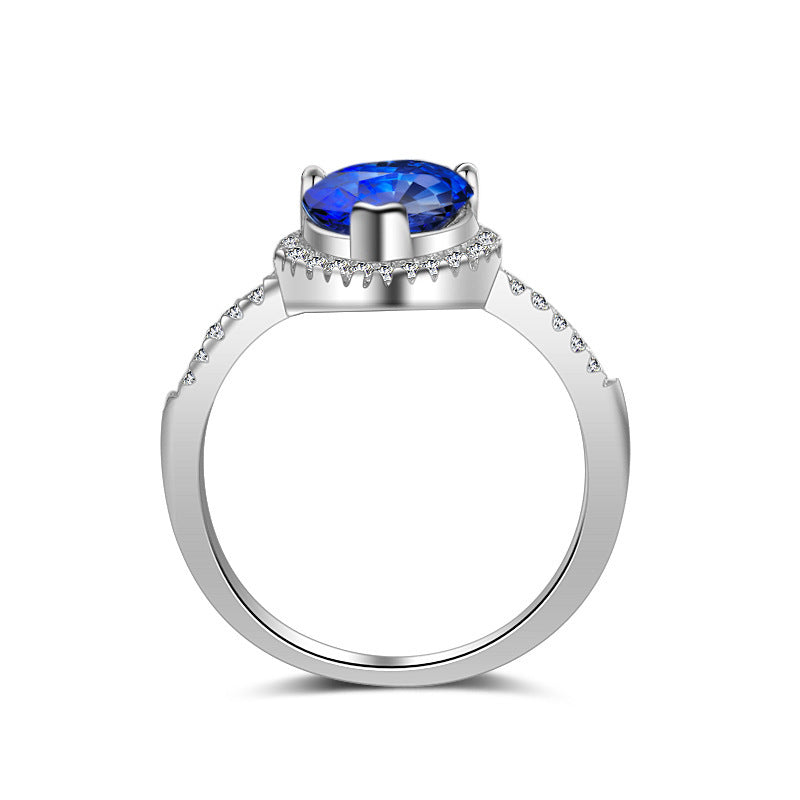 Diamond ring with a silver band, blue oval center stone, and pavé diamond accents