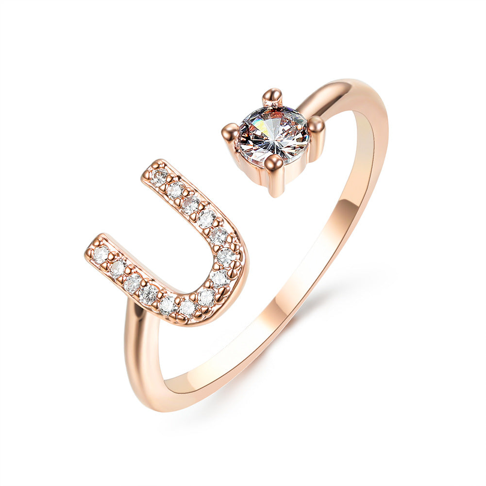Ring, rose-gold adjustable open U-shape with pavé crystals along one arm and a solitaire stone.