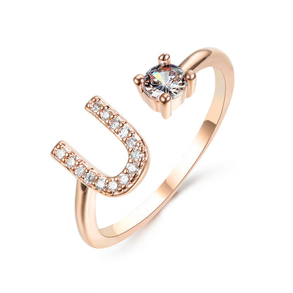 Ring, rose-gold adjustable open U-shape with pavé crystals along one arm and a solitaire stone.