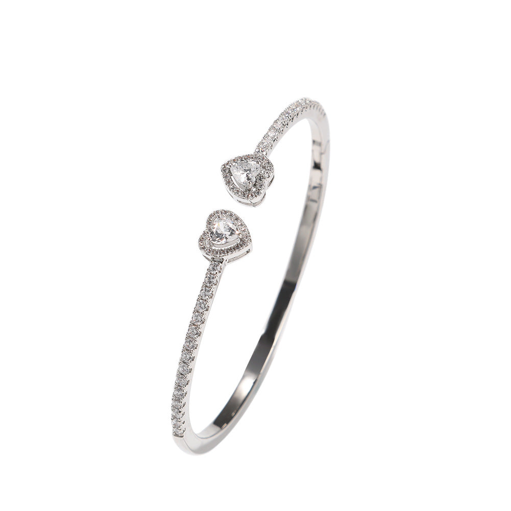 CJ heart-shaped diamond bracelet with pavé diamonds on a silver-toned band