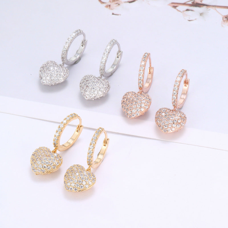 Six pairs of heart pendant pavé hoop earrings in silver, rose gold, and yellow gold tones