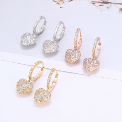 Six pairs of heart pendant pavé hoop earrings in silver, rose gold, and yellow gold tones