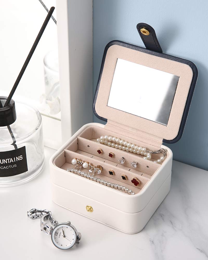 Portable jewelry box; white exterior, beige interior, mirrored lid, with pearl jewelry and bracelets.