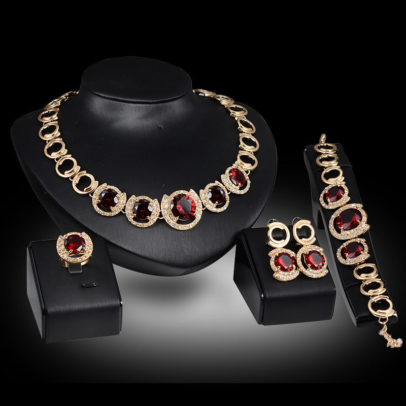 Gold-tone bridal jewelry set with red zircon and clear crystals; includes necklace, bracelet, ring, and earrings (5-piece).