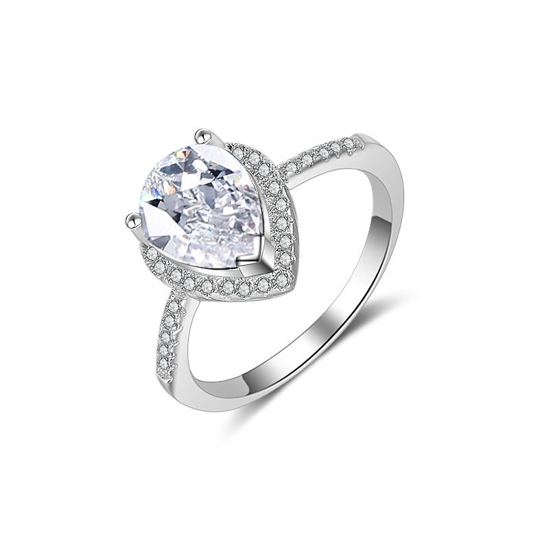 Diamond ring with pear-cut center stone, pave halo and band in silver.