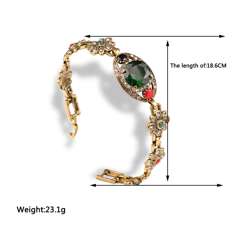Vintage ethnic-style bracelet by CJ; gold-tone with floral crystal accents and a central green gem, 18.6 cm long