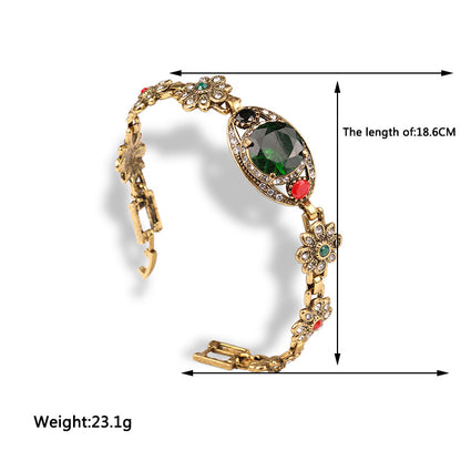 Vintage ethnic-style bracelet by CJ; gold-tone with floral crystal accents and a central green gem, 18.6 cm long