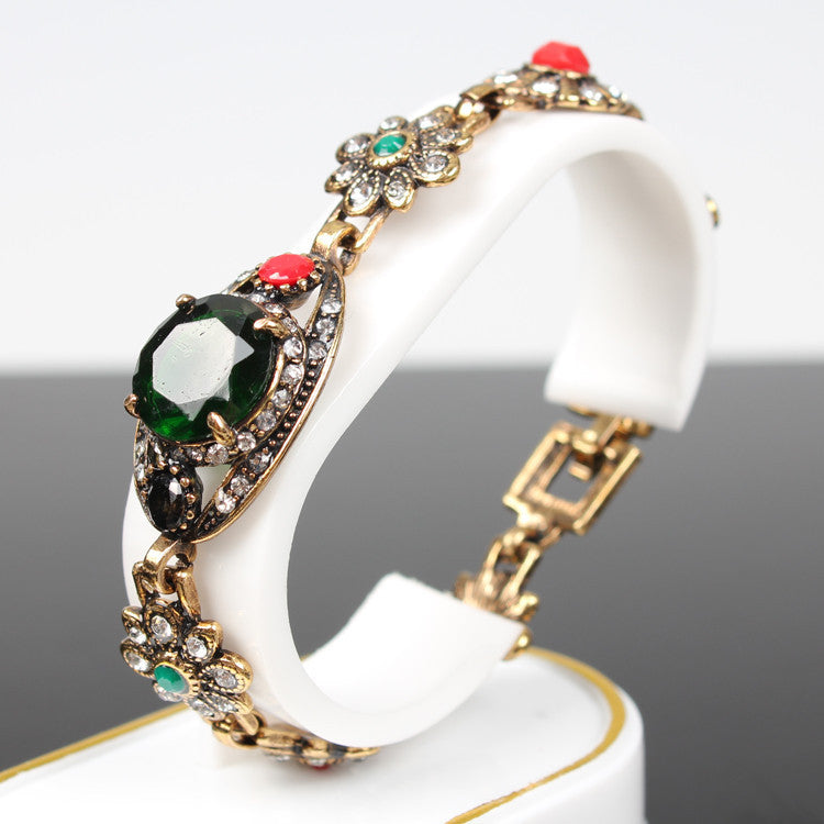 Vintage ethnic style bracelet with gold-tone metal and a large green central stone, accented by crystals.