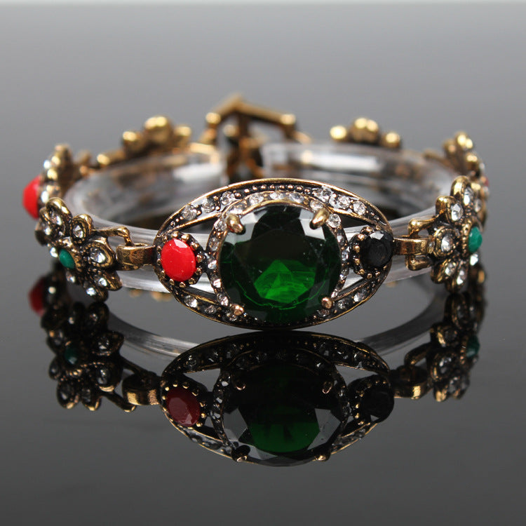 Vintage ethnic style bracelet in antique gold-tone with emerald center stone and crystal accents
