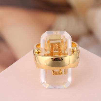 Rectangular natural stone ring in gold-tone metal with a clear crystal centerpiece.