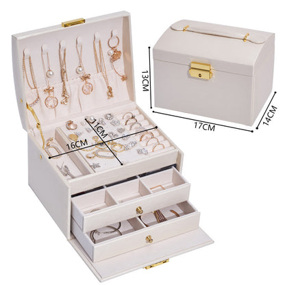 Three-layer cream jewelry storage box with necklace hooks, drawers, and gold hardware.
