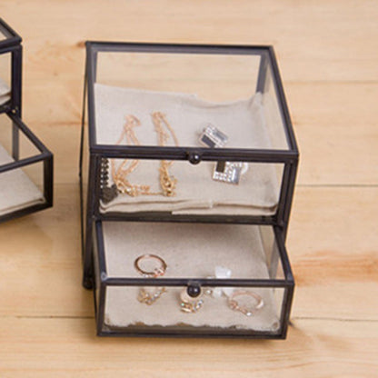 Jewelry storage display box with a black metal frame and glass lid, two drawers for rings and bracelets.