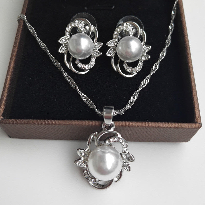 Three-piece bridal pearl jewelry set: silver-tone necklace with large pearl pendant and matching crystal earrings