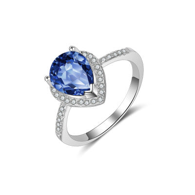 Diamond ring with blue pear-cut center stone and pavé halo on white gold band