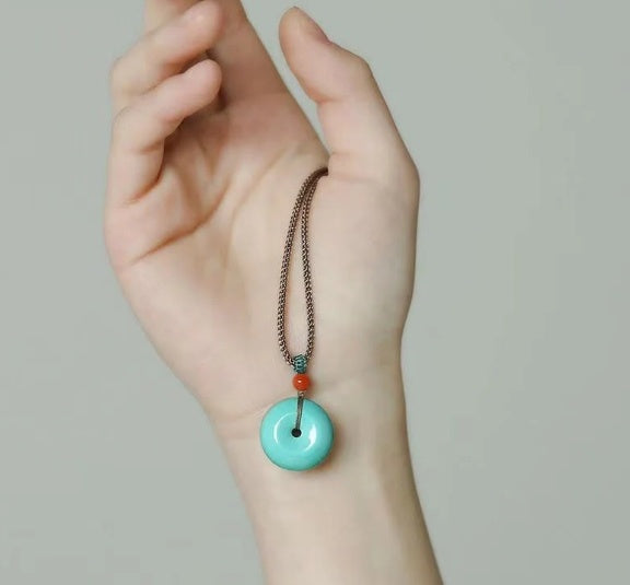 Turquoise donut pendant necklace with bronze chain and red accent bead.