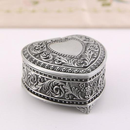 Heart-shaped silver jewelry box with ornate floral engraving for brooches and rings.