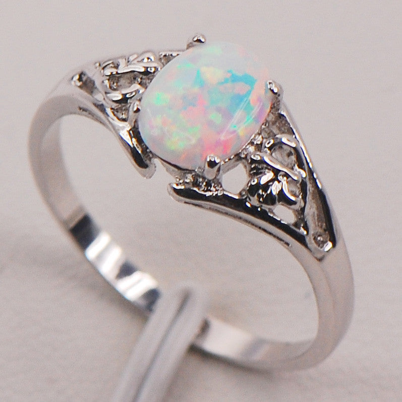 Ring with oval opal centerpiece in silver setting, filigree accents.