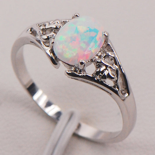 Ring with oval opal centerpiece in silver setting, filigree accents.