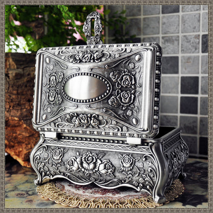 Vintage jewelry box in silver-tone metal with ornate rose engravings.