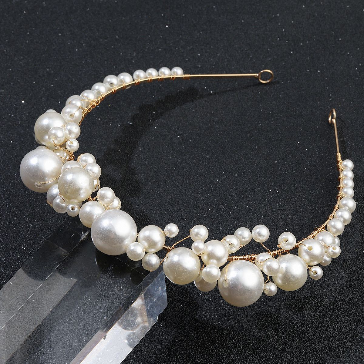 Retro bridal pearl headband with gold-tone wire and varying-size white pearls.