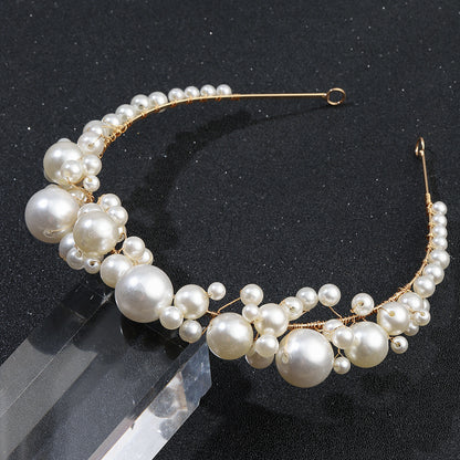 Retro bridal pearl headband with gold-tone wire and varying-size white pearls.
