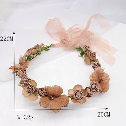 Bridal flower wreath hair accessory with peach and mauve fabric blossoms and a sheer ribbon bow.